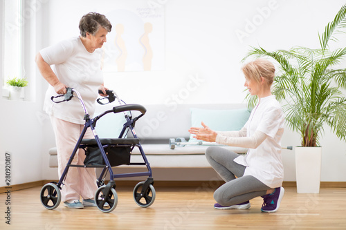 Bild auf Leinwand Senior woman with walker trying to walk again and helpful physiotherapist suppor