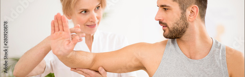 Fotografie Panoramic view of handsome young man during physiotherapy session with professio