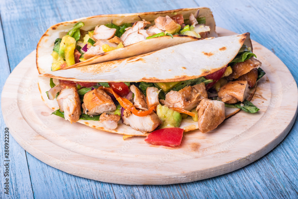 Tacos with vegetables, avocado and chicken breast on a wooden round board closeup - traditional mexican appetizer Tacos with vegetables, avocado and chicken breast on a wooden round board closeup - traditional mexican appetizer
