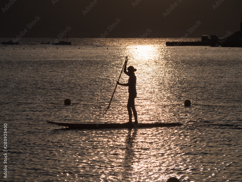 silhouette einer jungen Damen beim Paddeling im goldenen Abendlicht