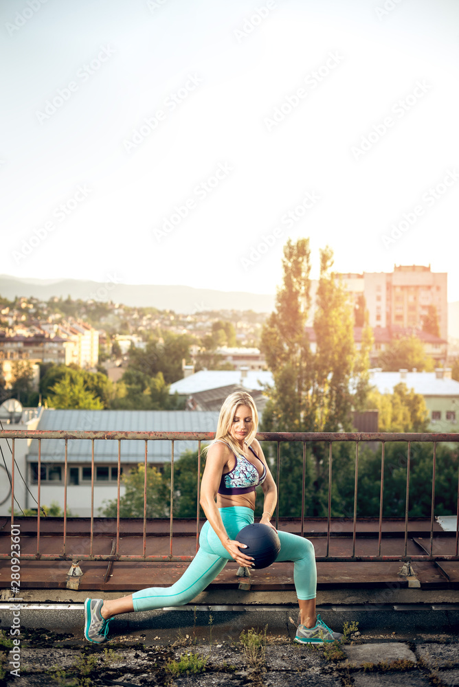 Woman doing exercise with medicine ball on rooftop.