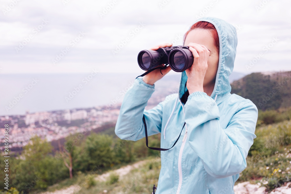Traveler young woman looking through binoculars in summer outdoor. Traveler young woman looking through binoculars in summer outdoor.