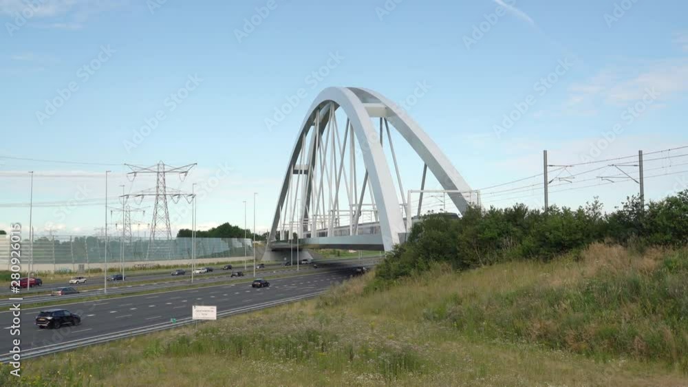 Train passing on the train bridge towards Flevoland crossing Commuters in cars driving on highway A1, Muiden, The Netherlands, July 9th 2019 Train passing on the train bridge towards Flevoland crossing Commuters in cars driving on highway A1, Muiden, The Netherlands, July 9th 2019
