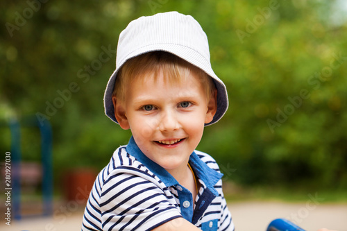 Portrait of a little blonde boy in a blue hat