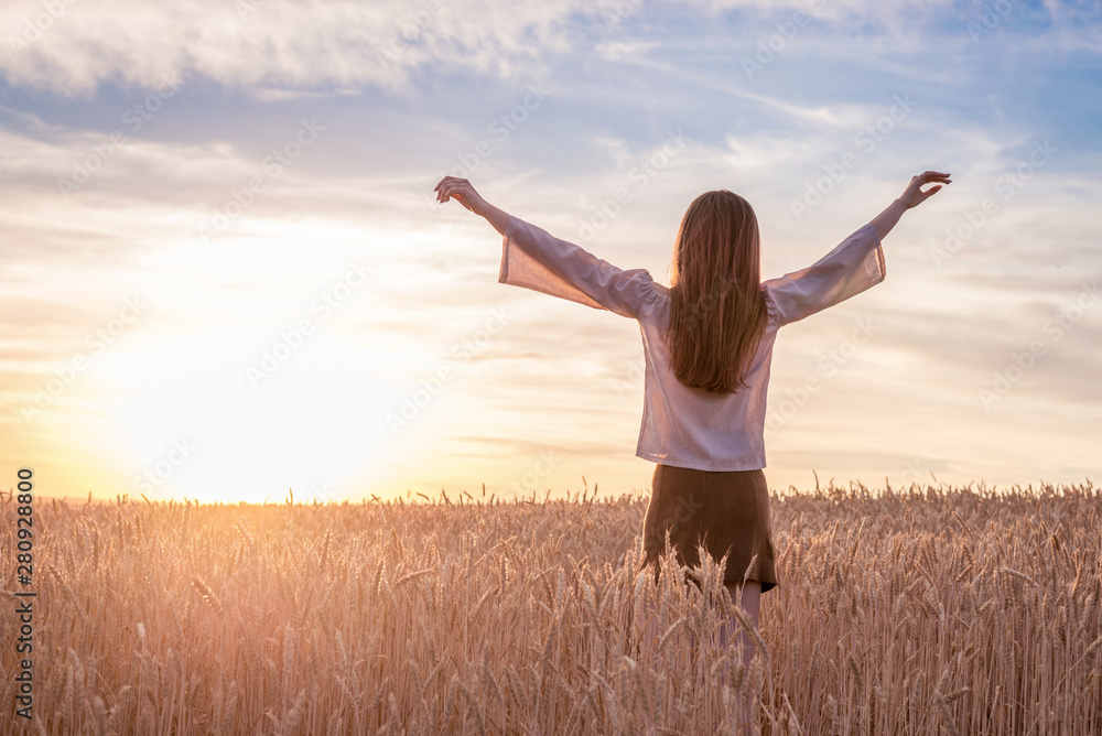 Beautiful girl in wheat field at golden sunset with open arms. enjoying at nature and summertime freedom Beautiful girl in wheat field at golden sunset with open arms. enjoying at nature and summertime freedom