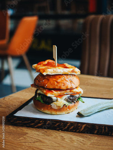 Big burger with beef cutlet, white bun and pepperoni pizza