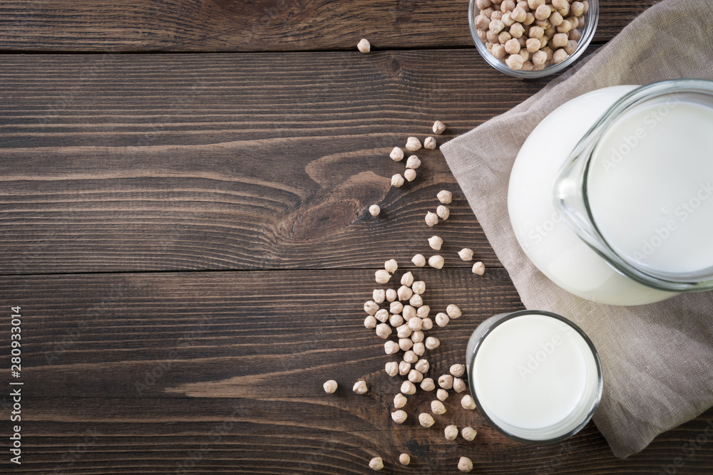 Fresh chickpea milk in glass and pitcher on dark wooden table. Rustic style. Fresh chickpea milk in glass and pitcher on dark wooden table. Rustic style.