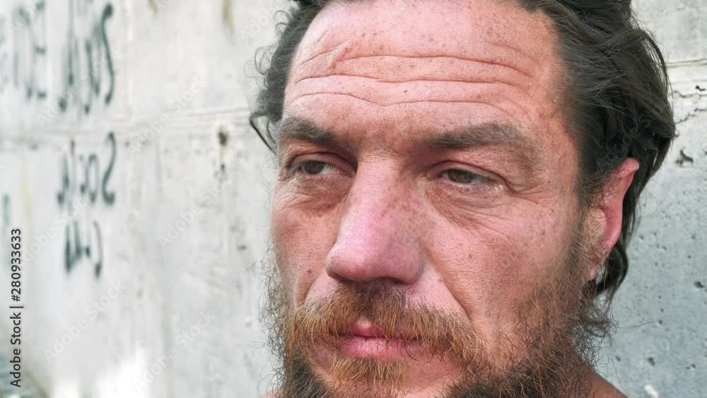 Slow motion close-up face of real homeless man. Real person with no fixed abode. Down-and-out person on the street. Degraded man looks at the camera, social degradation Slow motion close-up face of real homeless man. Real person with no fixed abode. Down-and-out person on the street. Degraded man looks at the camera, social degradation
