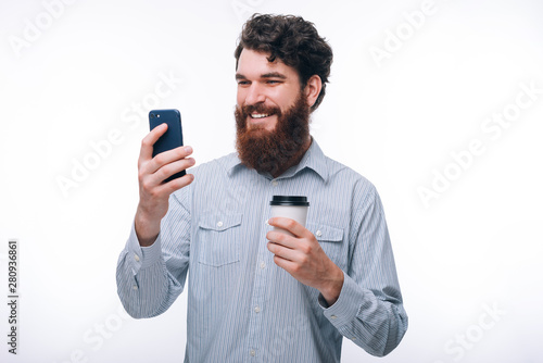 Photo of excited man using his smartphone and holding cup of coffee © Vulp