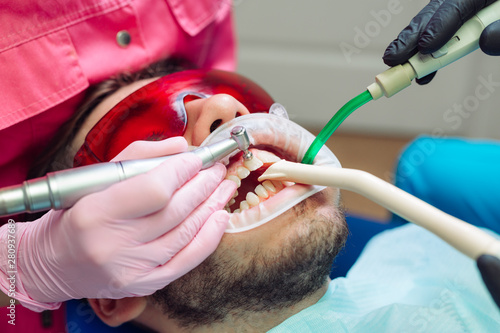 Professional teeth cleaning. Dentist cleans the teeth of a male patient.