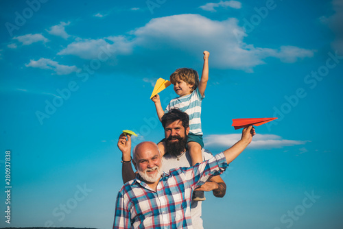 Portrait of happy father giving son piggyback ride on his shoulders and looking up. Dream of flying. Fathers day concept. Generation concept.