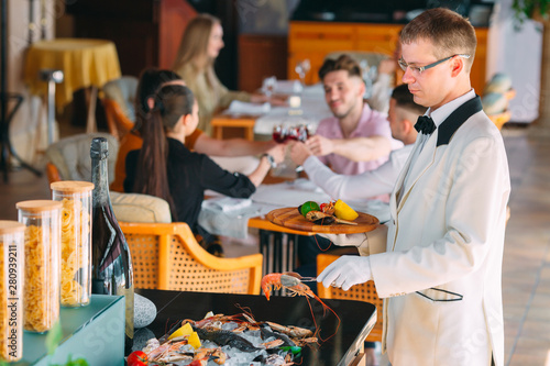 The waiter shifts the seafood on a tray in the restaurant. © davit85