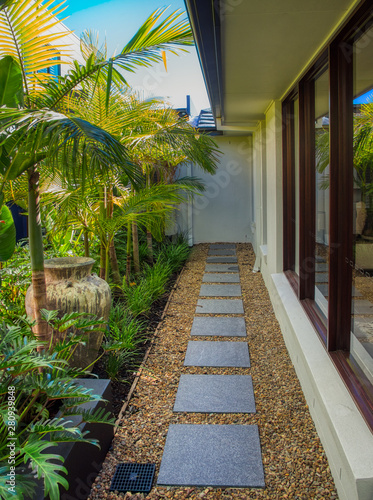 Grey stepping stones in pebbles and tropical garden