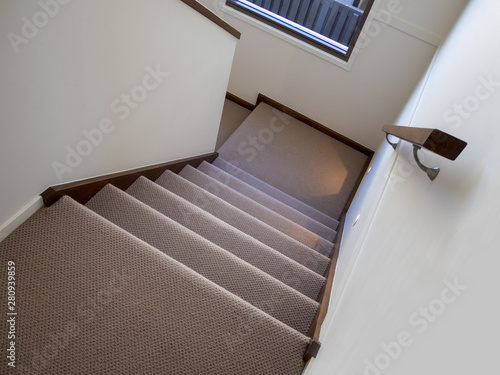 Modern carpeted staircase with night lighting and wooden handrail