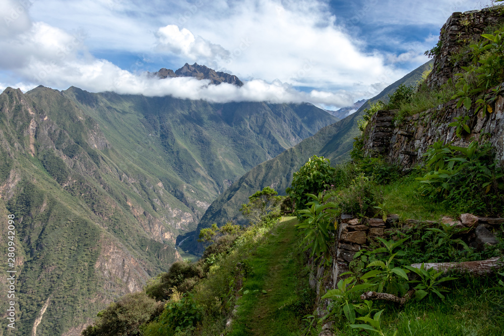 Pinchinuyok ancient Inca ruins surrounded by mountain peaks and clouds above the green canyon in Peru