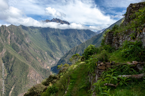 Pinchinuyok ancient Inca ruins surrounded by mountain peaks and clouds above the green canyon in Peru