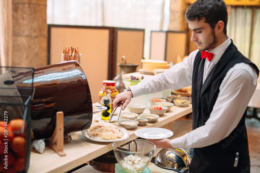 Fototapeta premium Sauerkraut. Breakfast at the hotel or restaurant. The waiter lays the sauerkraut in the dish.
