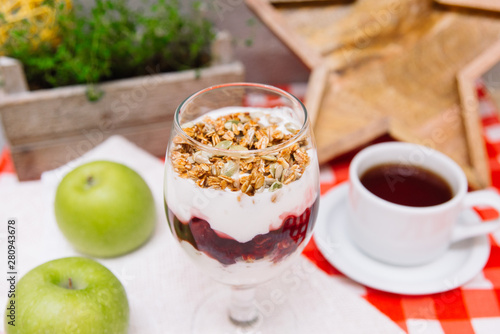 Cherry yoghurt parfait with crispy granola and cup of tea photo