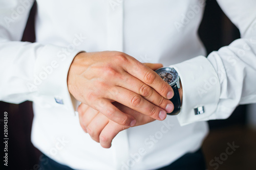 Close-up stylish watch on the groom's hand who looks at the dial