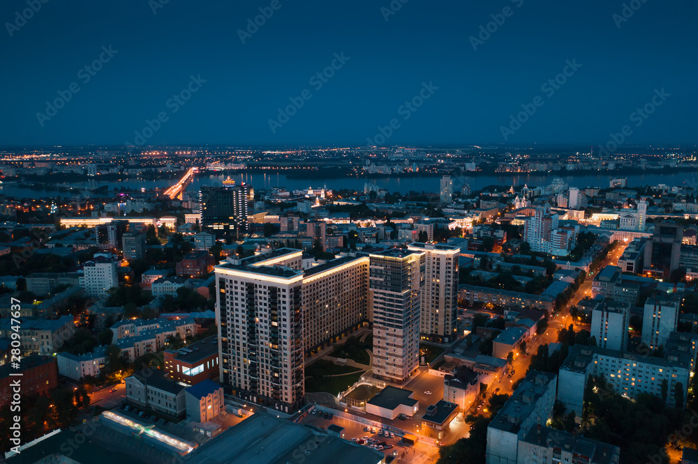 Night City downtown or center panorama from above with illuminated road intersection, car traffic, modern business and residential buildings, aerial view