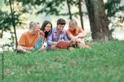 friends of students read books sitting on the lawn in the Park