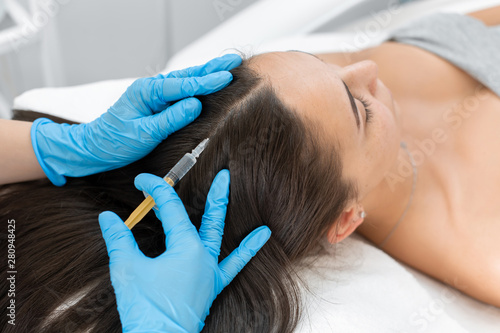 Beautician injections for healthy hair growth. Mesotherapy of the scalp. A young girl is undergoing a course of spa treatments in the office of a beautician. Moisturizing