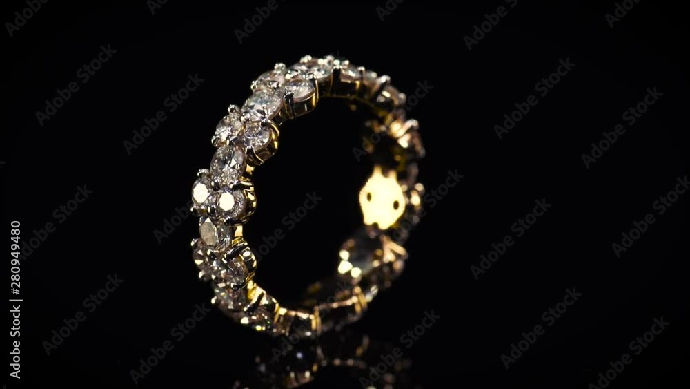 Gold wedding ring with shining diamonds on black mirror background. Gold wedding ring with shining diamonds on black mirror background.
