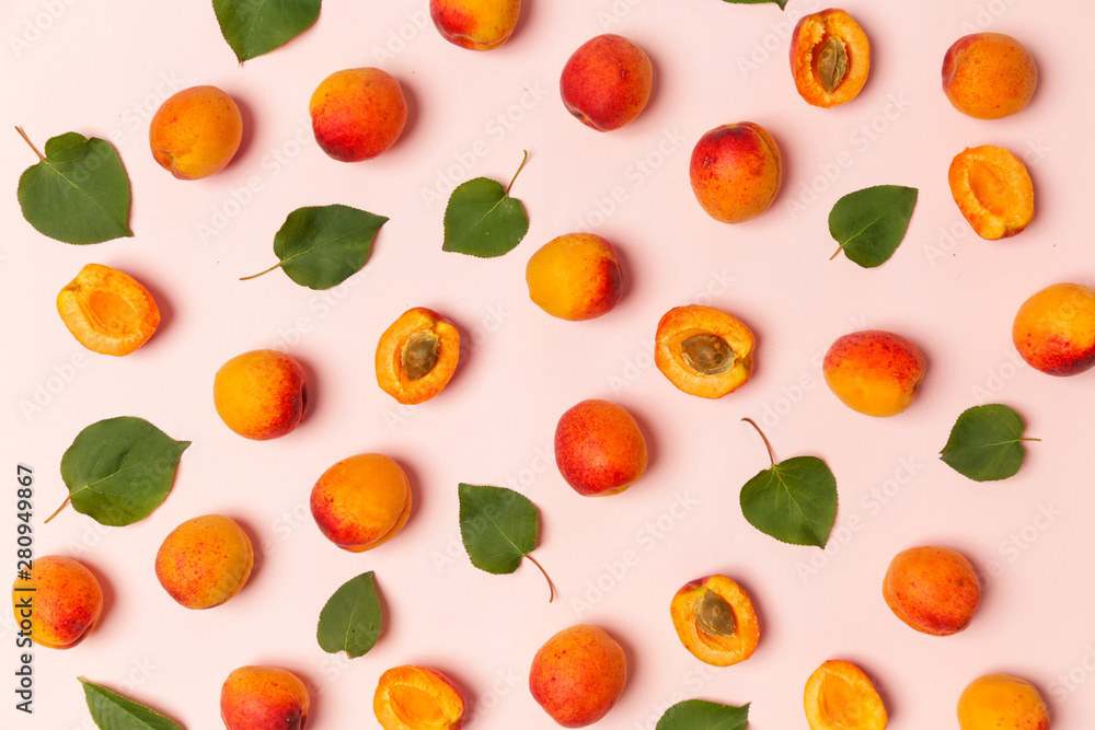 Apricots on a pink background, the flat lay image of ripe apricots and leaves Apricots on a pink background, the flat lay image of ripe apricots and leaves