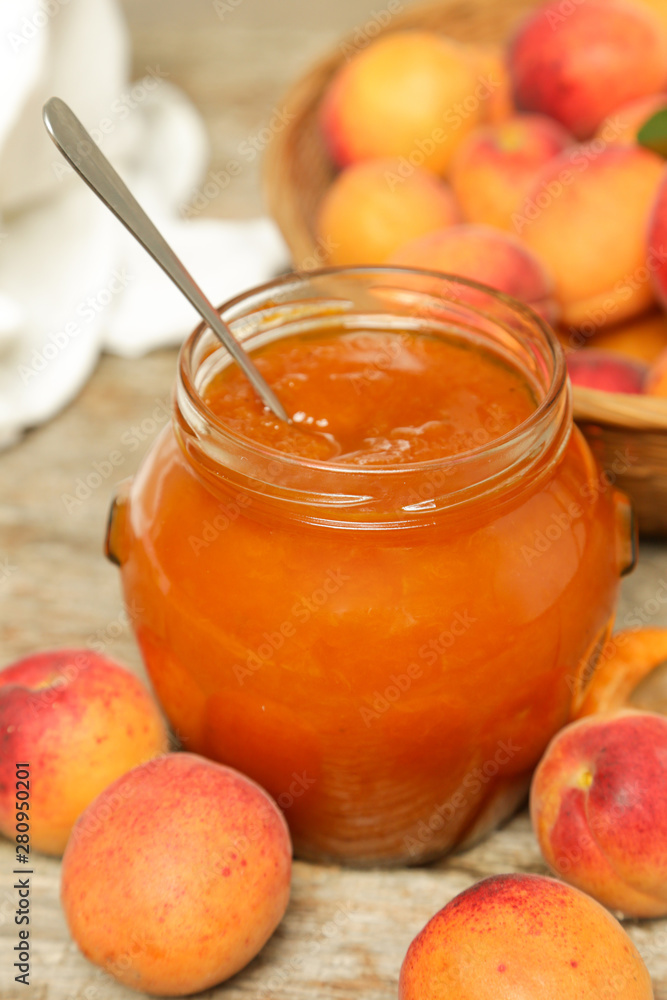Jar of apricots jam and fresh apricots on wooden background Jar of apricots jam and fresh apricots on wooden background