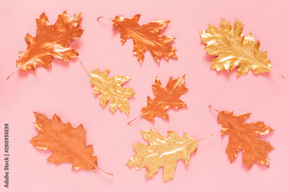Autumn composition with a gold and copper spray painted natural leaves on pink background. Flat lay, top view, copy space. Autumn composition with a gold and copper spray painted natural leaves on pink background. Flat lay, top view, copy space.
