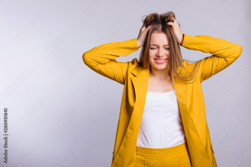 strong headache in a young woman in a yellow suit. white backgro strong headache in a young woman in a yellow suit. white backgro