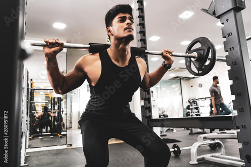 Man at the gym. Execute exercise squatting with weight, in gym