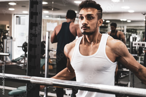 Man at the gym. Execute exercise squatting with weight, in gym