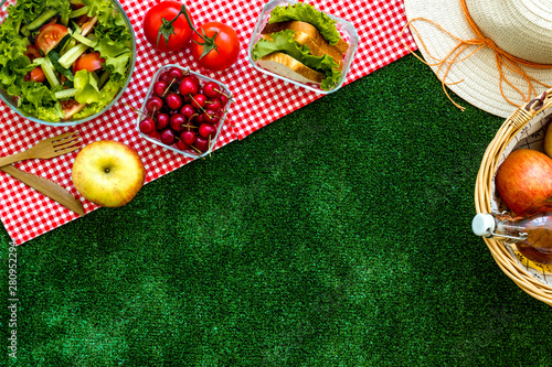 picnic in summer with products, sandwich, salad, fruits, drink and hat on green grass texture background top view mockup