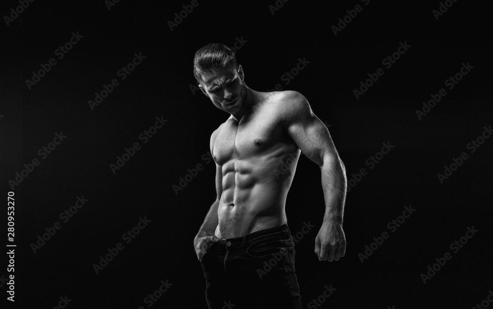 Black and white. Muscular model sports young man on dark background.  Fashion portrait of strong brutal guy with a modern trendy hairstyle. Sexy  torso. Male flexing his muscles. Stock Photo | Adobe