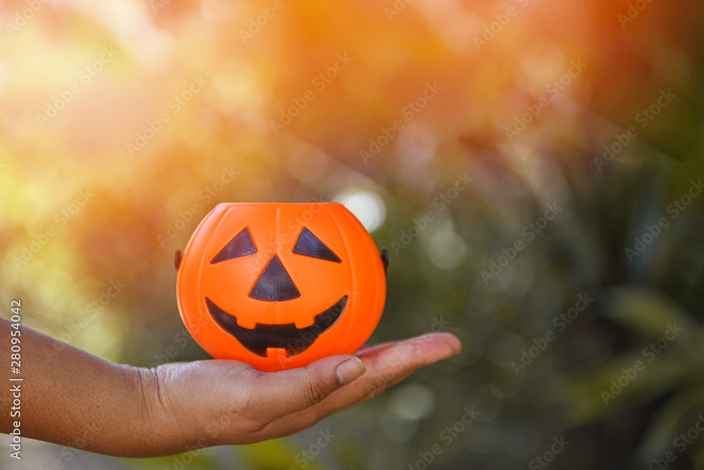 Naklejka premium Halloween pumpkin lantern on hand - head jack o lantern evil faces spooky holiday decorate on halloween nature background