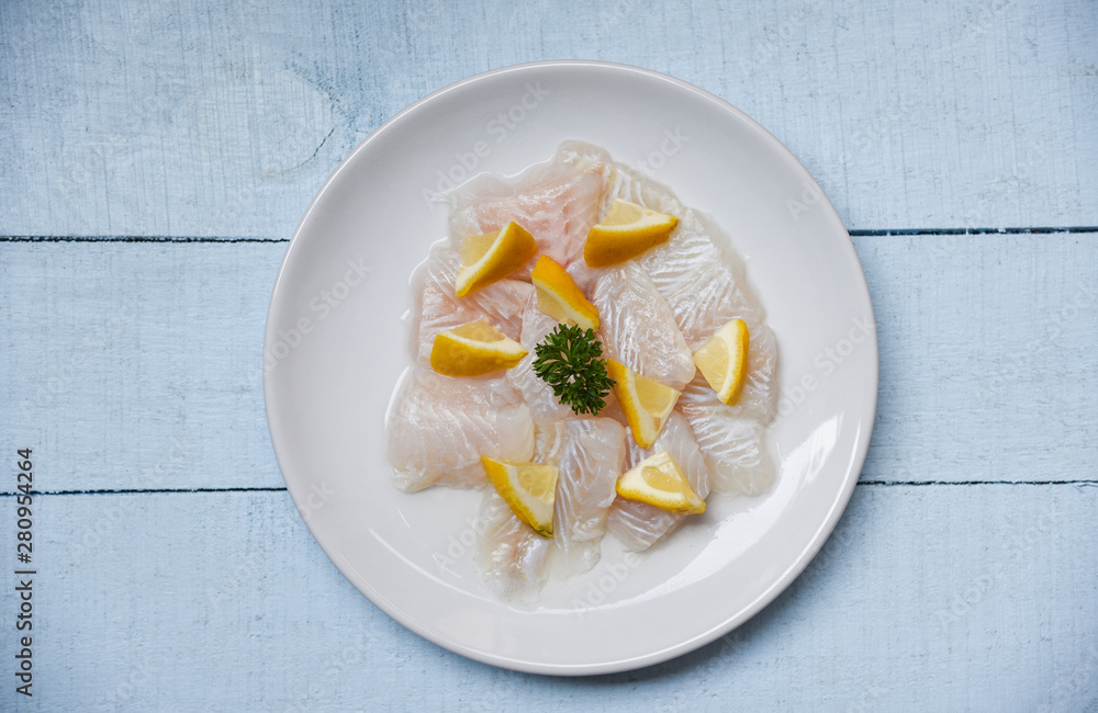 Raw fish fillet piece with lemon on white plate - Close up pangasius dolly fish meat