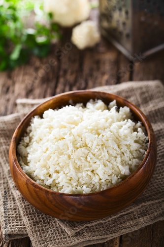 Freshly grated raw cauliflower rice in wooden bowl (Selective Focus, Focus one third into the image)