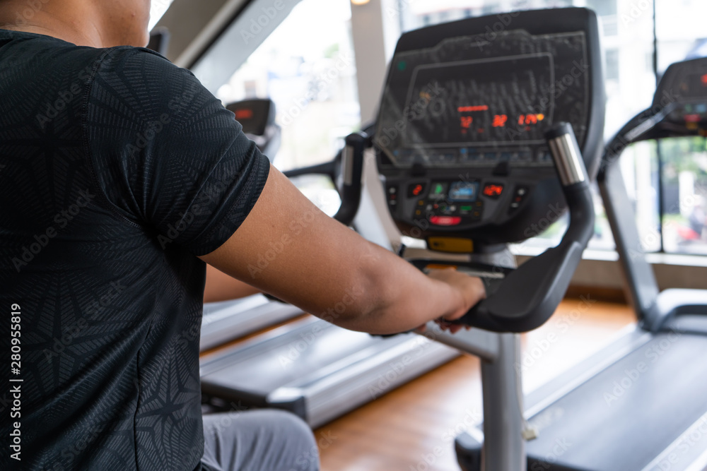 Smiling mature man in sportswear riding a stationary bike while working out alone at the gym Smiling mature man in sportswear riding a stationary bike while working out alone at the gym