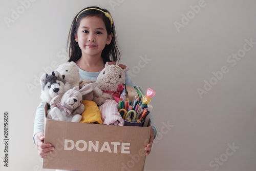 Photography Mixed Asian young volunteer girl holding a box full of used old toys, cloths, bo