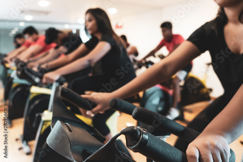 Fit people working out at spinning class in gym