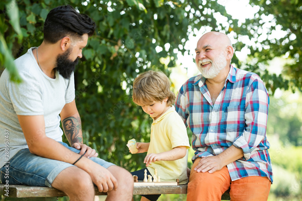 Cute little boy playing chess with Parents. Generation of people and stages of growing up. Male Multi Generation Family. Cute little boy playing chess with Parents. Generation of people and stages of growing up. Male Multi Generation Family.