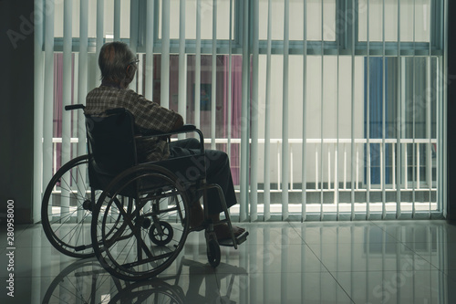 Lonely old man in the wheelchair near the window