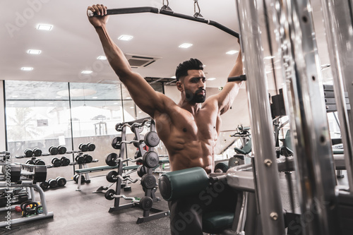 Fit man on lat pulldown machine at the health club. Work out on Pulldown Weight Machine