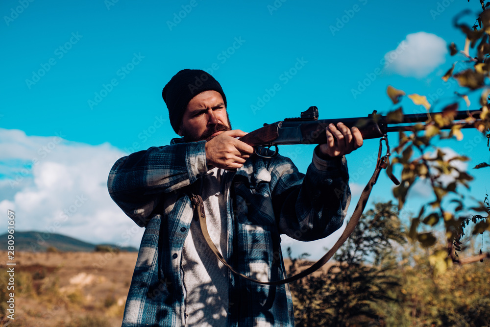 Bearded hunter man holding gun and walking in forest. Hunter with shotgun gun on hunt. Big game. Bearded hunter man holding gun and walking in forest. Hunter with shotgun gun on hunt. Big game.