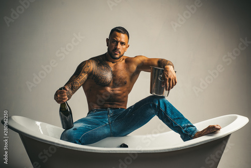 Celebrate achievement. Champagne celebration in luxury bathtub. Handsome attractive man tattooed body drinking expensive champagne. Night party. Celebrate purchase real estate. Celebrate luxury life