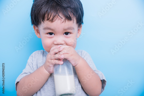 Asian little child boy about 2 year drinking milk from bottle glass
