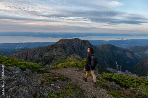 Adventurous girl hiking the beautiful trail in the Canadian Mountain Landscape during a vibrant summer sunset. Taken at Mt Arrowsmith  near Nanaimo  Vancouver Island  BC  Canada.