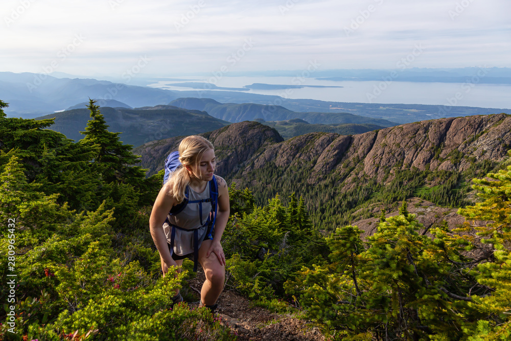 Adventurous girl hiking the beautiful trail in the Canadian Mountain Landscape during a vibrant summer evening. Taken at Mt Arrowsmith, near Nanaimo, Vancouver Island, BC, Canada.