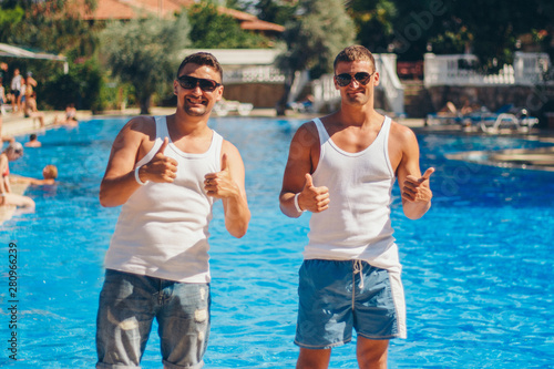 the concept of recreation, tourism - two smiling inflated men with glasses having fun by the pool